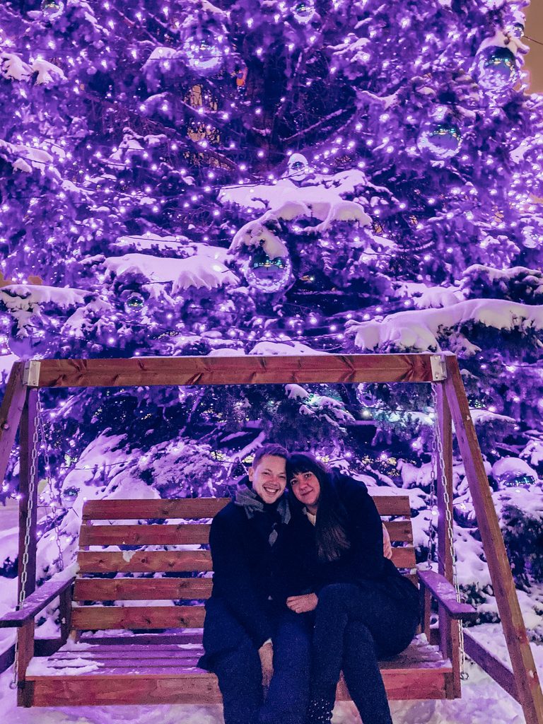 Couple sitting under Christmas lights in snowy Tallinn