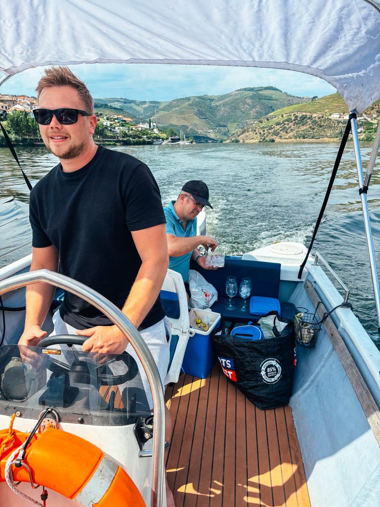 Mait steering our boat on the Douro River while our host prepares Porto Tónicos behind him