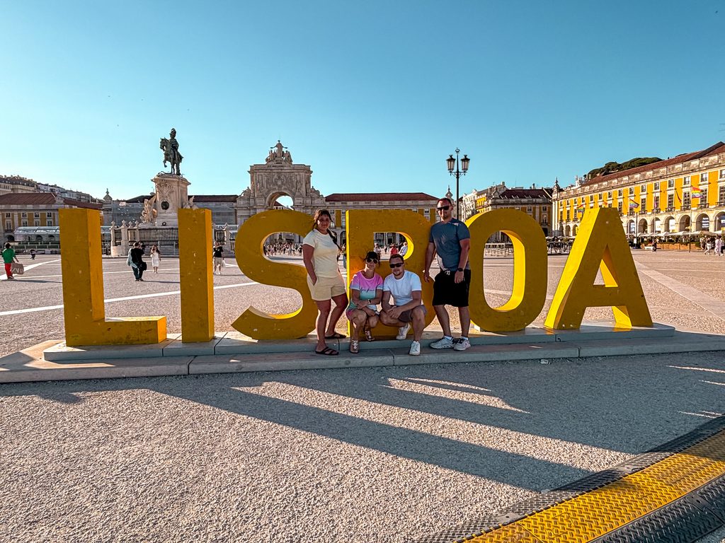 Our group at the yellow LISBOA sign in Praça do Comércio after a full day of sightseeing.