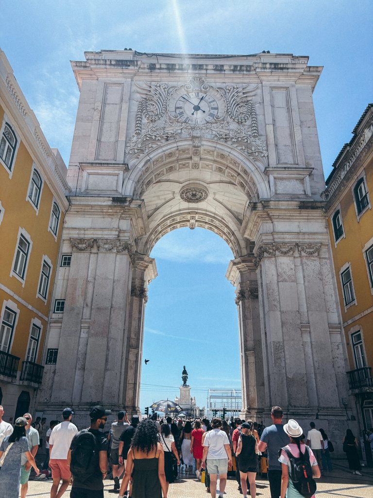 Arco da Rua Augusta in Lisbon with pedestrians walking towards Praça do Comércio.