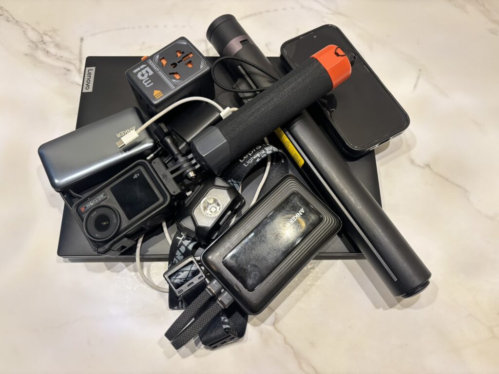 Electronics and camera gear for long-term travel including power banks, DJI Action 4, tripod and travel adapter