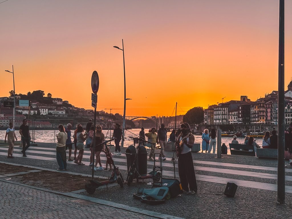 Street performer beside the Douro River at sunset in Porto