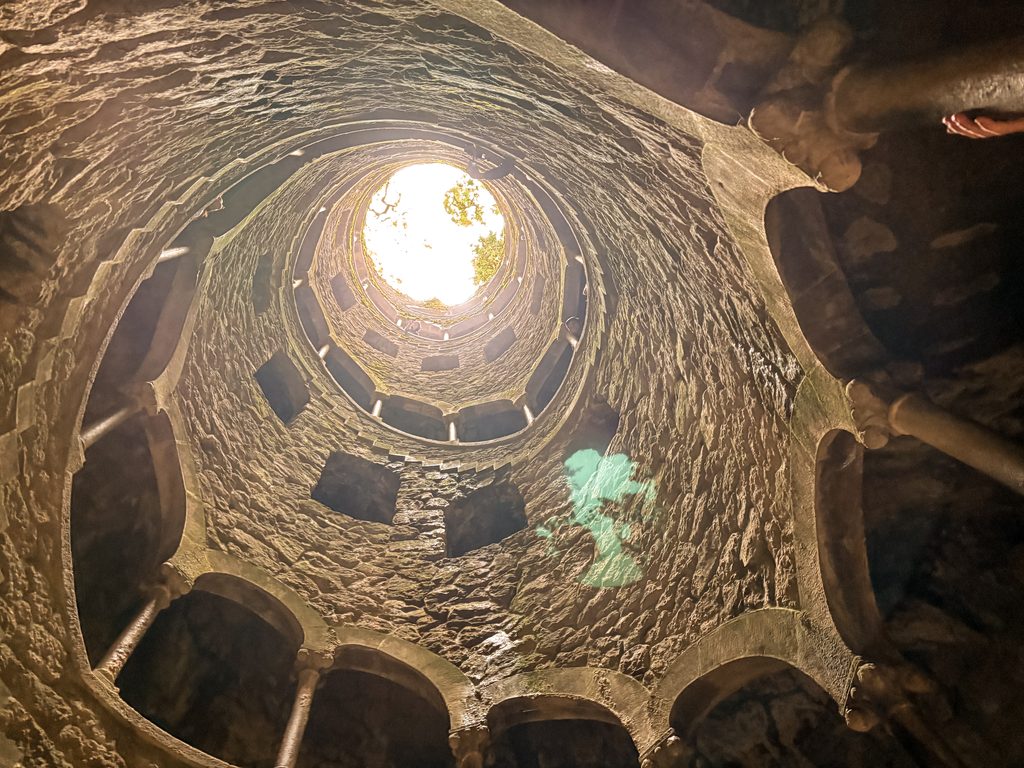 Looking up from the Initiation Well at Quinta da Regaleira towards the circular opening and daylight above.